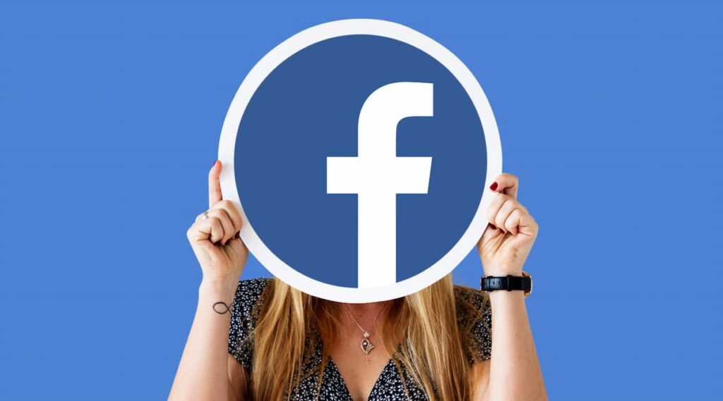 Uma mulher segurando um cartaz com o logotipo do facebook, representando a criação de uma copy para anúncios do facebook||
